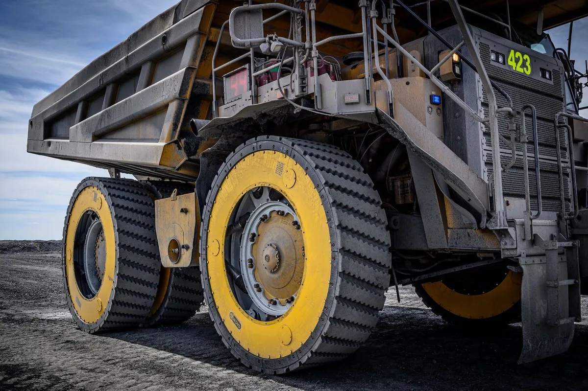 Mining haul truck fitted with Global Air Cylinder Wheels’ yellow-and-black Air Suspension Wheels on a gravel mine site under a blue sky