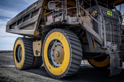 Mining haul truck fitted with Global Air Cylinder Wheels’ yellow-and-black Air Suspension Wheels on a gravel mine site under a blue sky