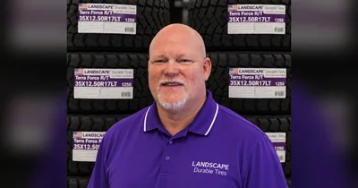 Chad Britton in a purple Landscape Durable Tires polo shirt in front of stacked Landscape Terra Force R/T tires