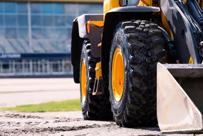 Low close-up of a yellow wheel loader on Nokian Ground King Loader tires with yellow rims, its bucket in the foreground