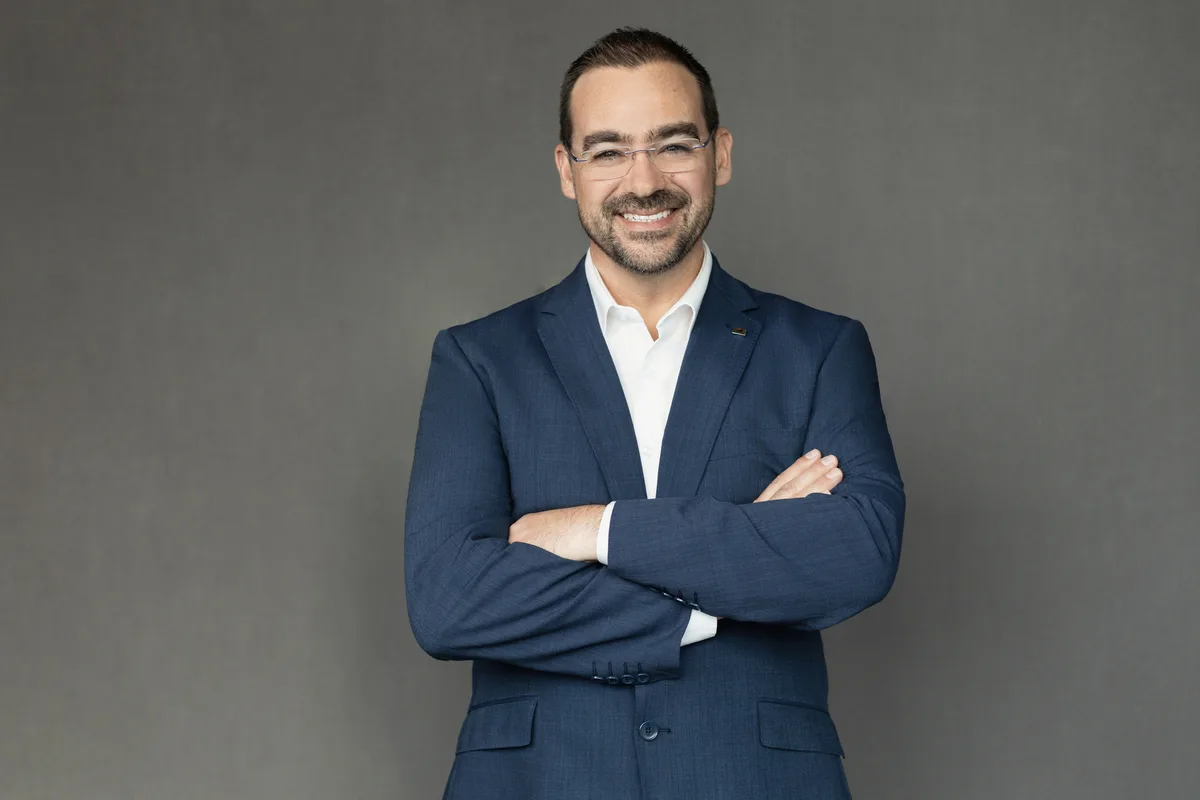 Jacques Fourie, President, Canada, Bridgestone, in a navy suit with arms folded against a grey backdrop