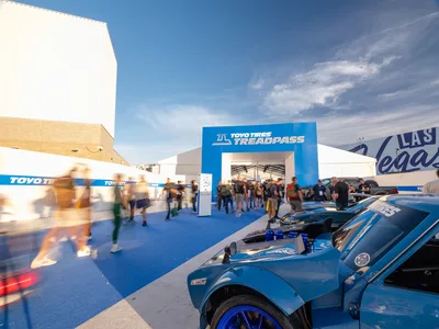 Toyo Tires Treadpass entrance arch at the SEMA Show in Las Vegas with attendees walking past a blue custom car on Toyo Proxes tires