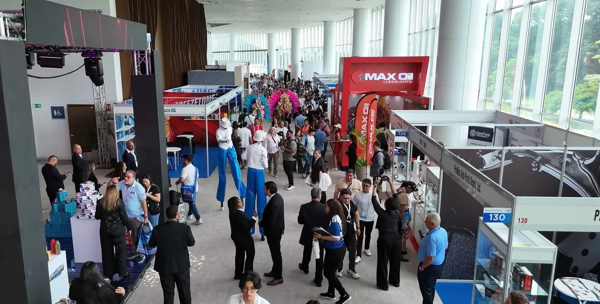 Attendees crowd an exhibition hall aisle lined with exhibitor booths at the Latin Tyre & Auto Parts Expo in Panama City