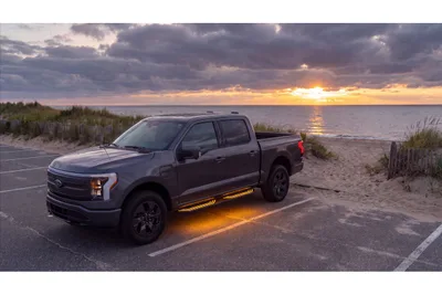 Pickup truck fitted with RealTruck Velocity 360 running boards with LED underglow, parked by the beach at sunset